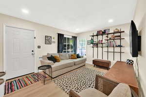 Living room with baseboards, wood finished floors, a textured ceiling, and recessed lighting