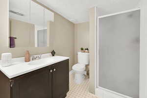 Full bath featuring tile patterned floors, a stall shower, vanity, toilet, and visible vents