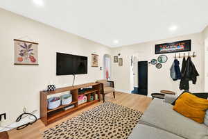 Living area with recessed lighting, baseboards, arched walkways, and light wood-type flooring