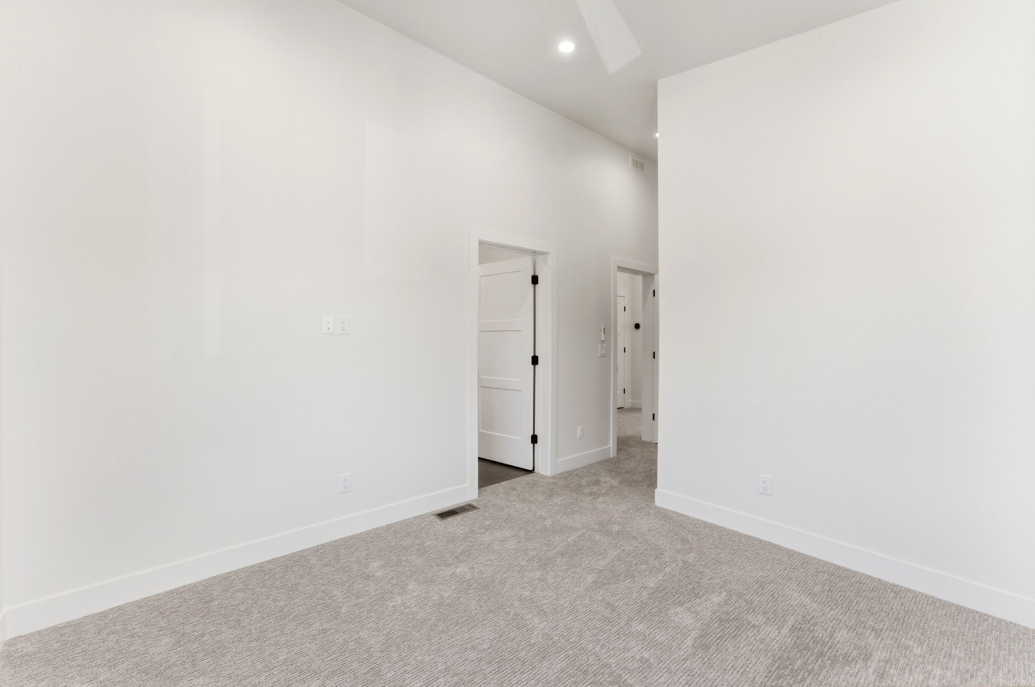 Carpeted room featuring white walls, white baseboards, and a white ceiling fan with integrated lighting