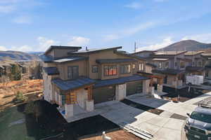 View of front of home featuring a mountain view, driveway, stone siding, and a garage