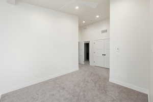 Unfurnished room with recessed lighting, a towering ceiling, and carpet flooring
