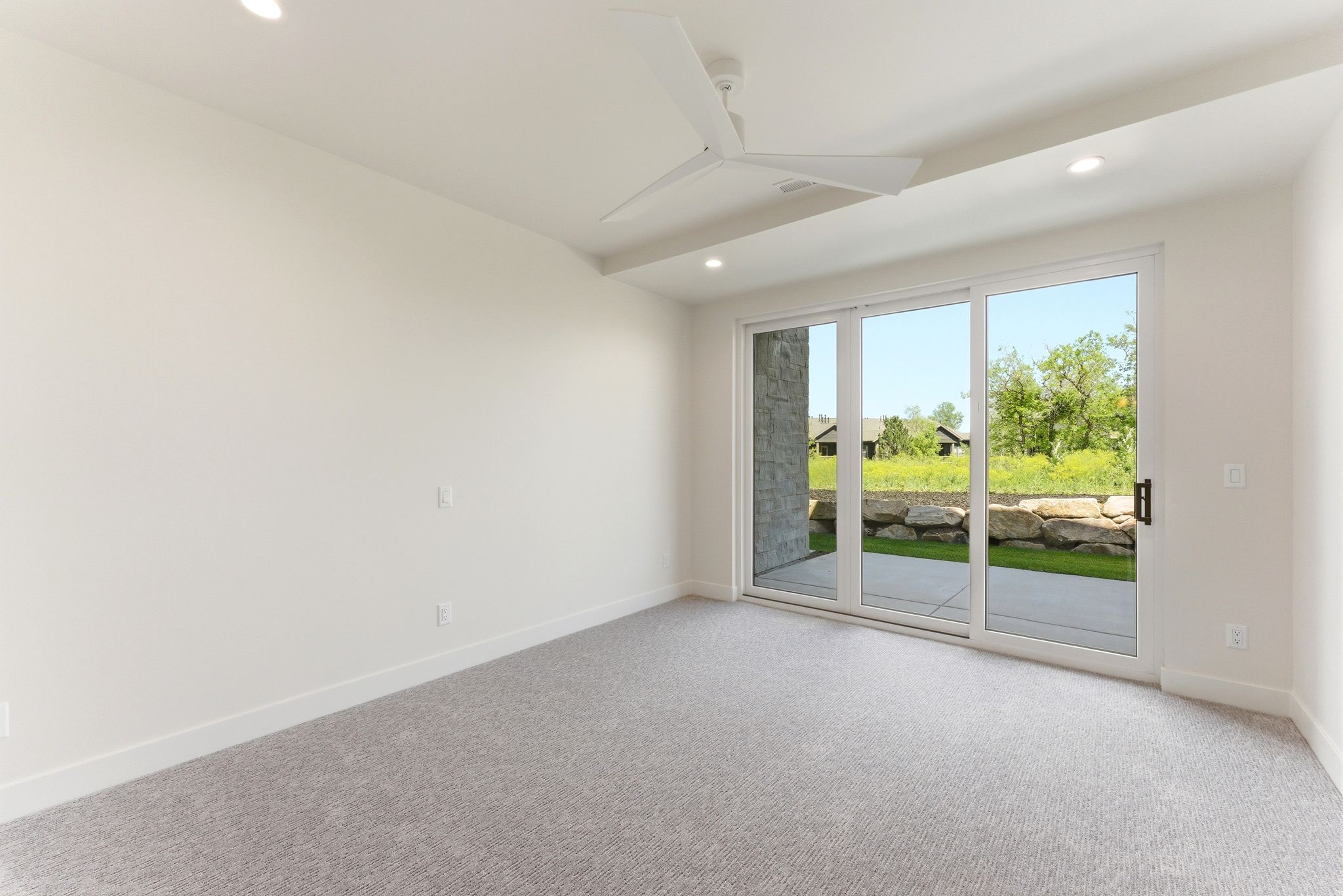 Bright interior space featuring light gray carpeting, recessed lighting, and a modern ceiling fan