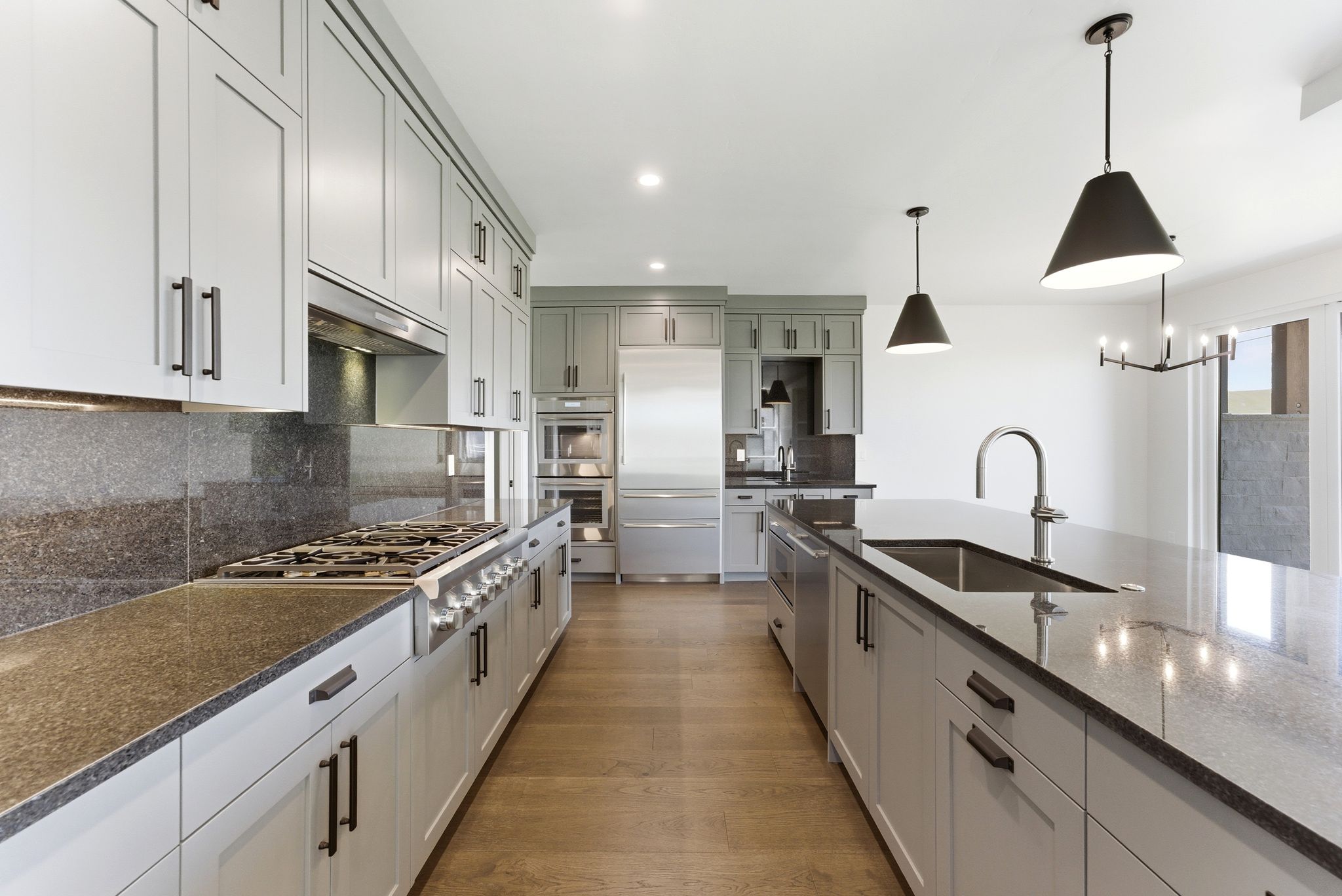 Gourmet kitchen featuring light gray cabinetry, dark countertops, professional-grade stainless steel appliances, and wood-finish flooring