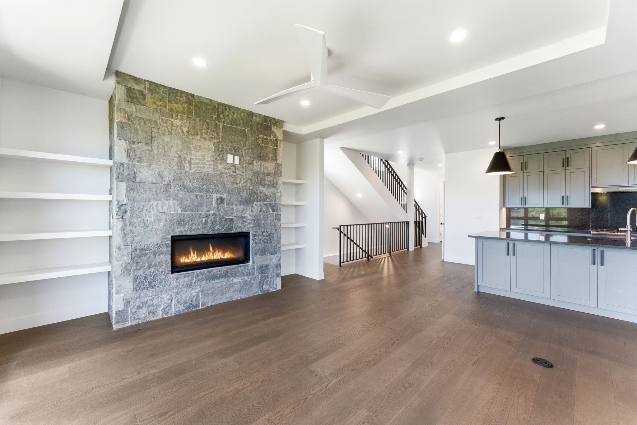 Stone fireplace with a linear firebox flanked by built-in shelving