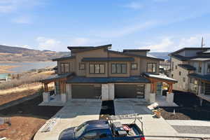 Contemporary home with a water view, an attached garage, concrete driveway, a patio, and a gazebo