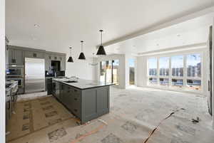 Kitchen featuring hanging light fixtures, stainless steel appliances, a kitchen island, open floor plan, and light stone countertops