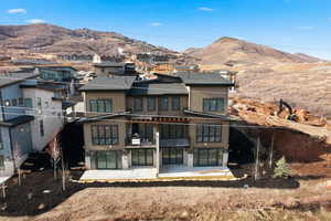 Back of property featuring a patio, a mountain view, a shingled roof, and a balcony