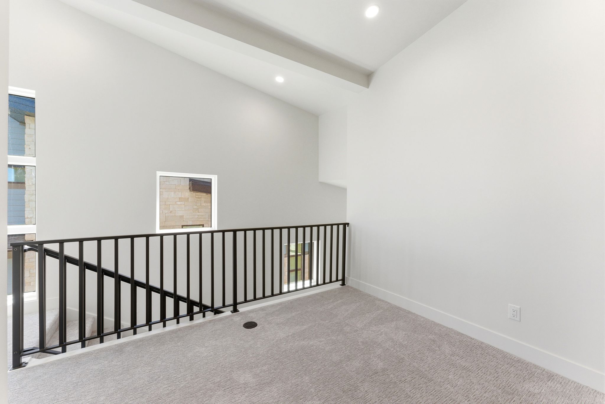 Loft area featuring a contemporary black metal railing, vaulted ceiling, recessed lighting, and light gray carpeting