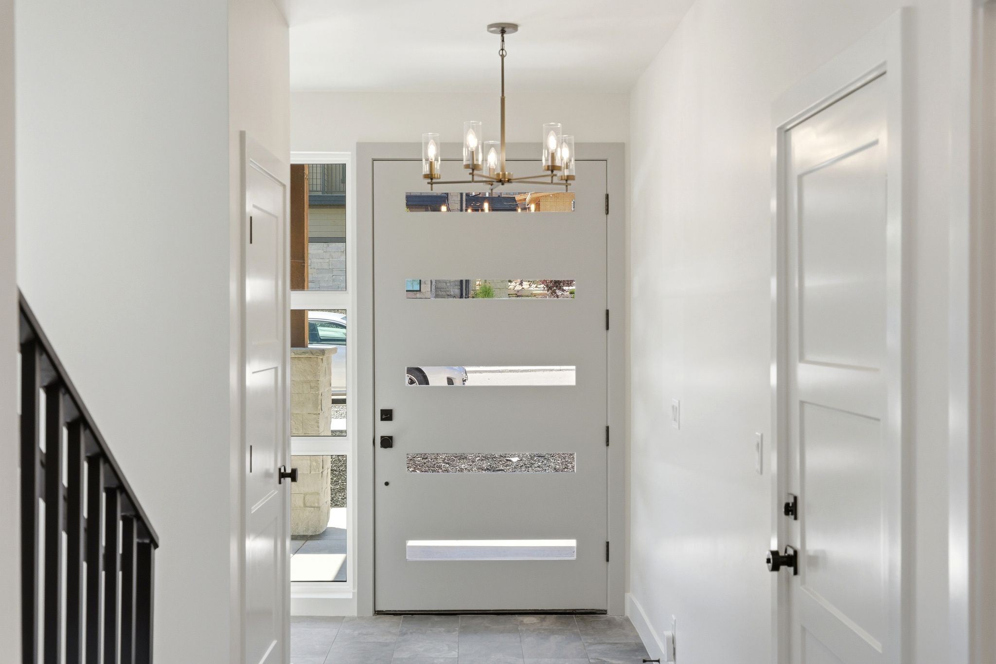 Entryway featuring a modern door with horizontal lites, a multi-light chandelier, and grey tile flooring