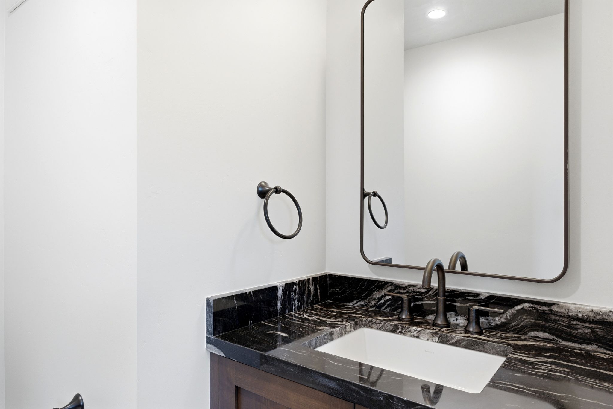 Modern vanity featuring a dark stone countertop with white undermount sink