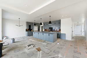 Kitchen with gray cabinets, a chandelier, a spacious island, and decorative light fixtures