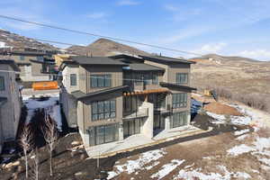Snow covered house featuring a patio area, a mountain view, and a balcony