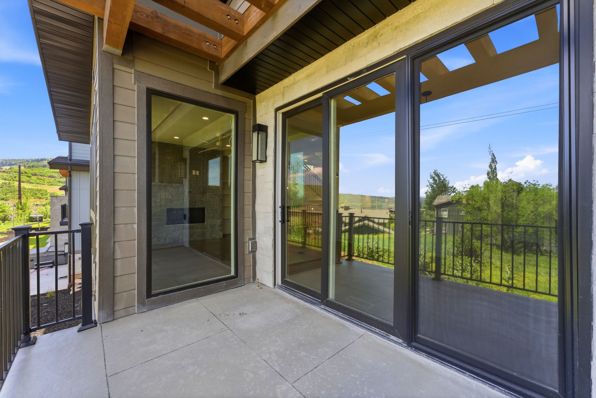 Outdoor patio featuring concrete flooring, black metal railings, and natural wood ceiling accents