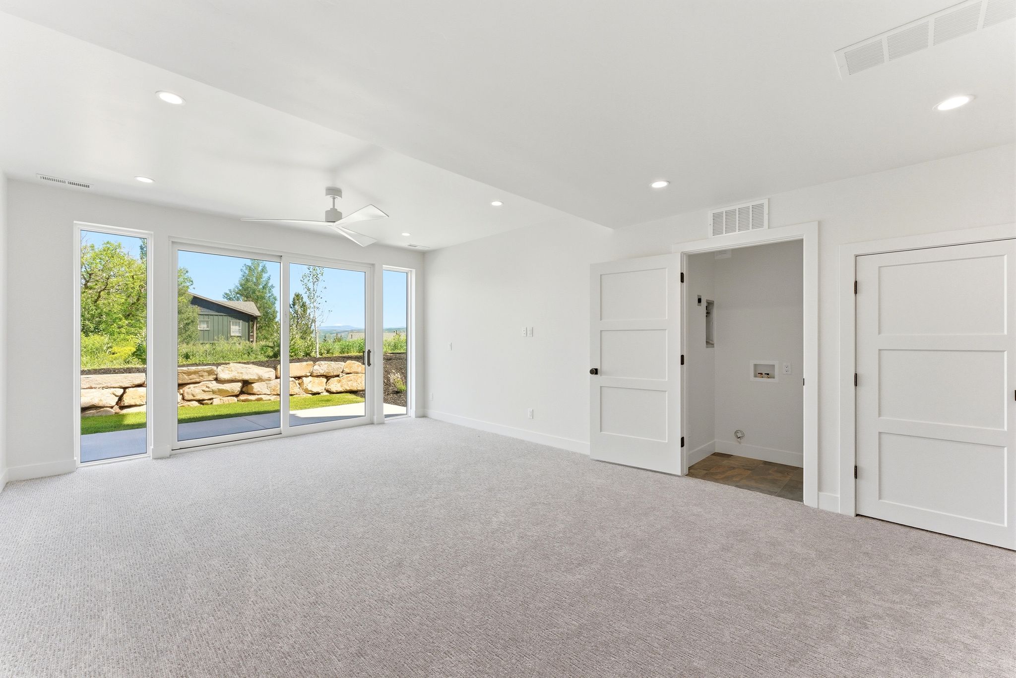 Bright interior room featuring a full wall of glass with a sliding door opening to a private exterior patio