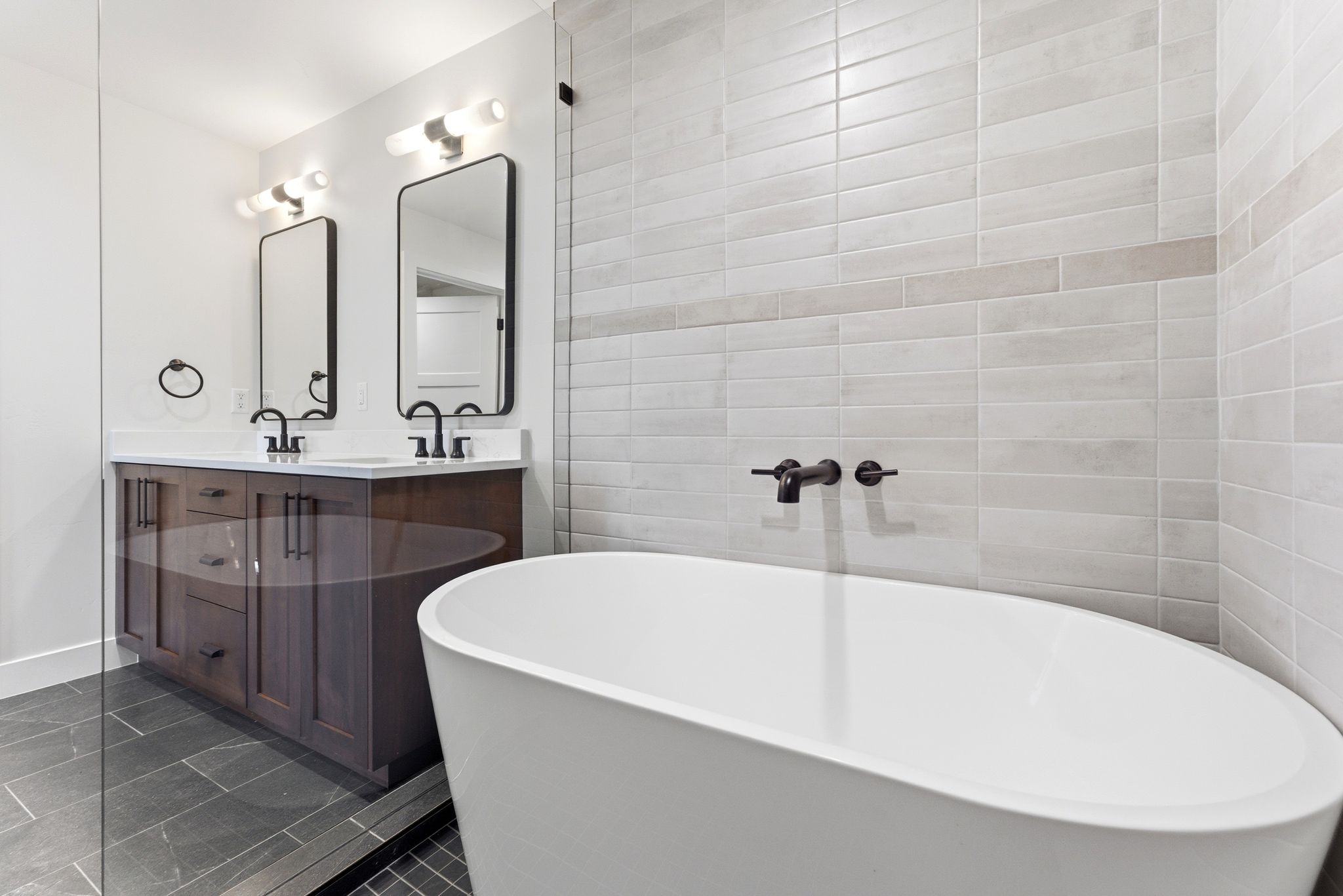 Freestanding soaking tub with wall-mounted matte black fixtures