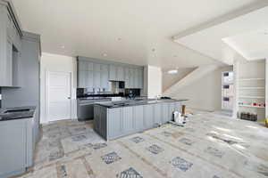 Kitchen featuring gray cabinets and a center island with sink