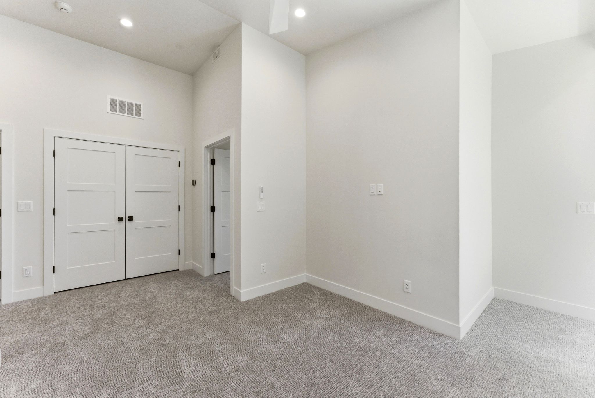 White paneled double doors with black hardware, recessed lighting, ceiling fan, and light gray carpet