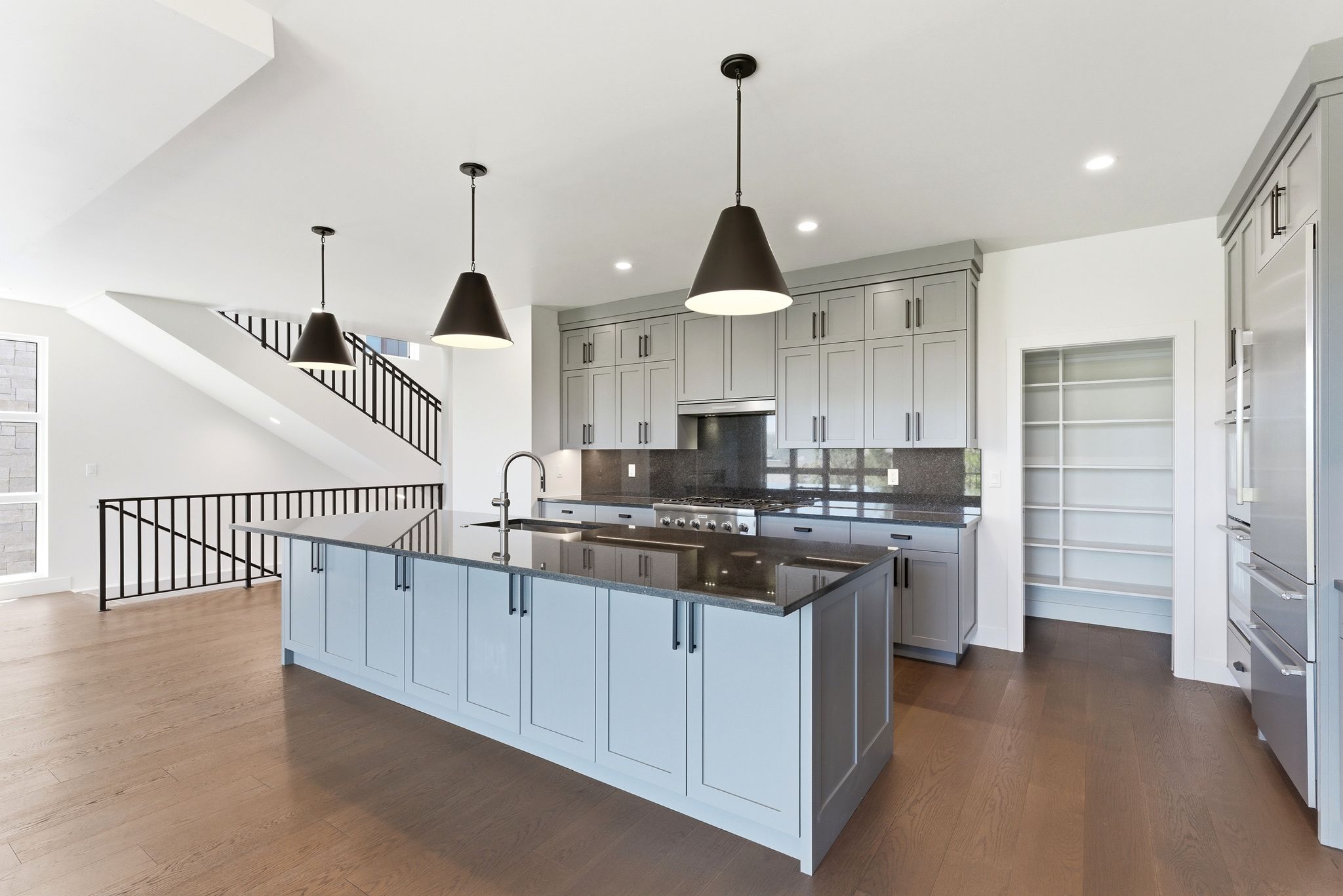 Gourmet kitchen featuring a large central island, light gray cabinetry, dark countertops, and stainless steel appliances