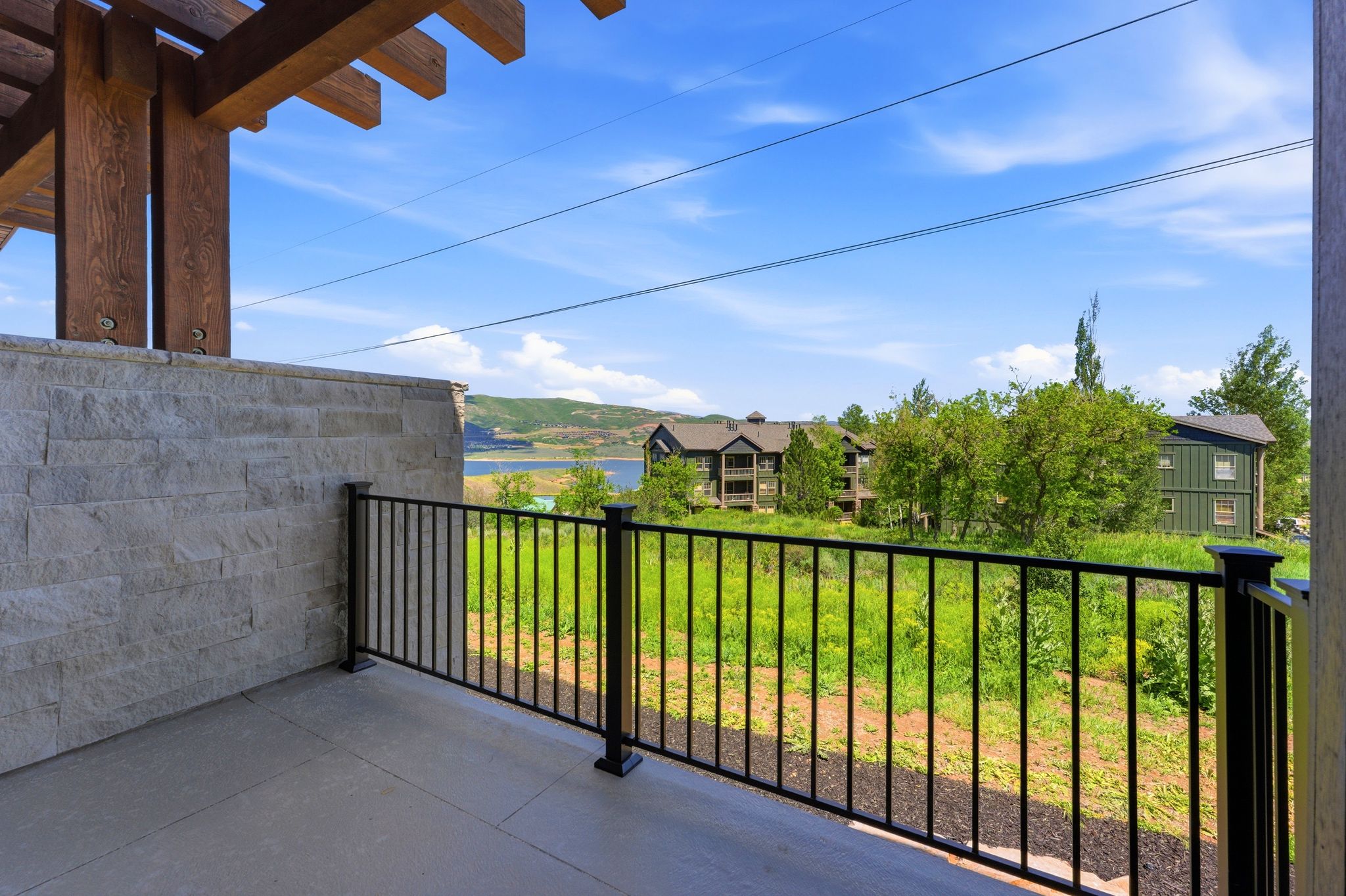 Outdoor patio featuring a solid stone wall, wood pergola, and metal railing