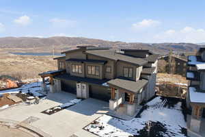Contemporary house with a mountain view, a garage, driveway, a shingled roof, and a porch