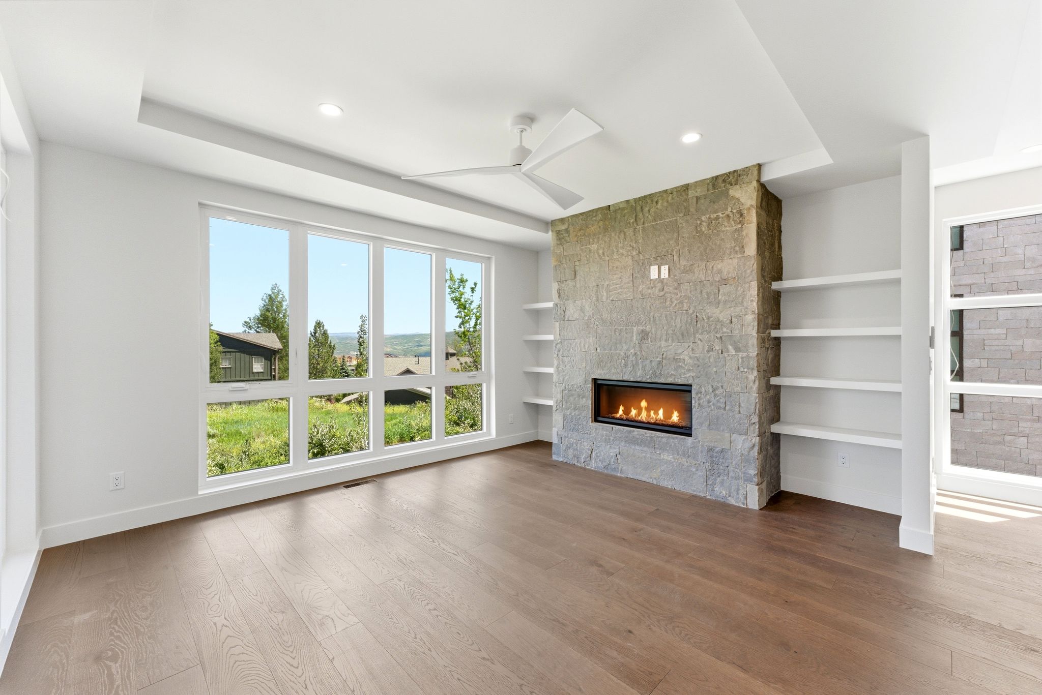 Spacious room featuring wood-finish flooring, a contemporary ceiling fan, and recessed lighting