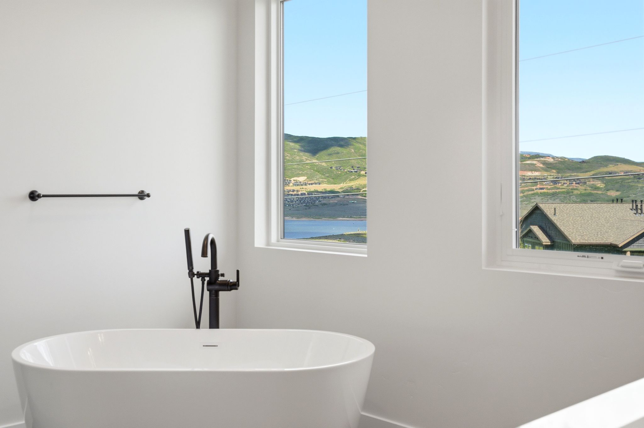 Freestanding soaking tub with matte black floor-mounted faucet and handheld shower