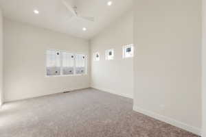 Spare room featuring a ceiling fan, carpet flooring, and lofted ceiling