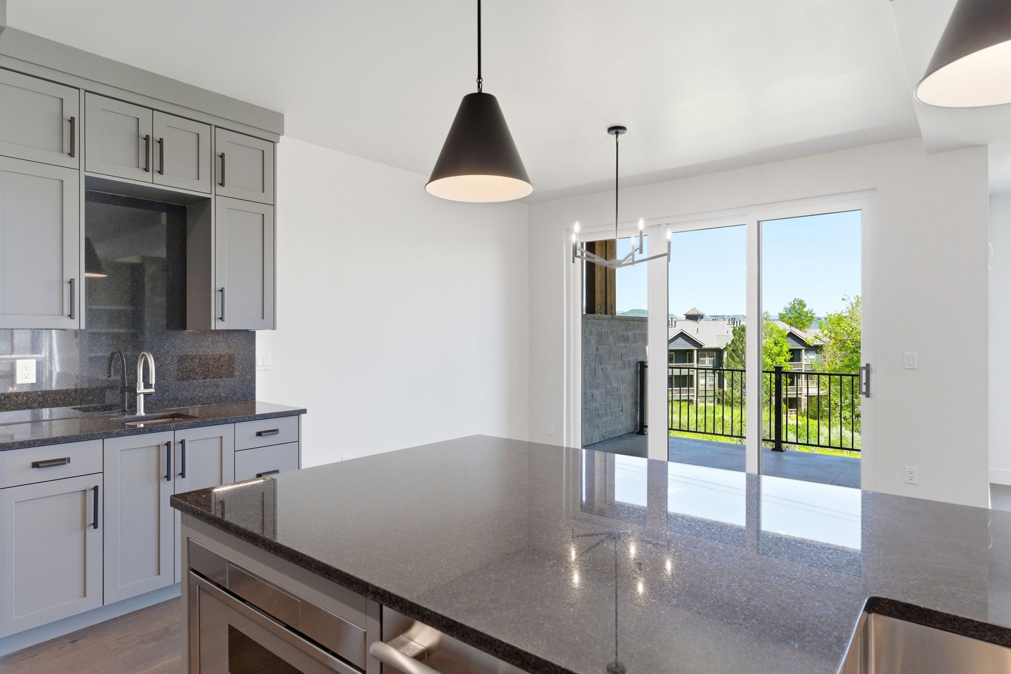Spacious kitchen featuring gray shaker cabinetry, dark stone countertops, stainless steel appliances, and a large center island