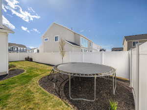 View of yard featuring a fenced backyard, a residential view, and a trampoline