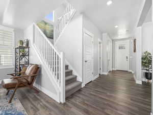 Entryway with stairway, baseboards, and dark wood-style floors