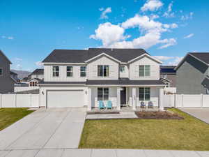 Traditional-style home featuring a front lawn, concrete driveway, board and batten siding, covered porch, and a garage