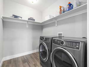 Clothes washing area featuring separate washer and dryer, baseboards, wood finished floors, and laundry area