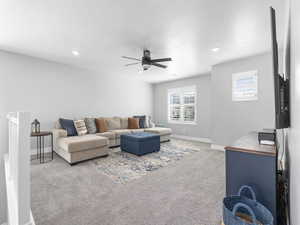 Carpeted living room featuring baseboards, a ceiling fan, and recessed lighting
