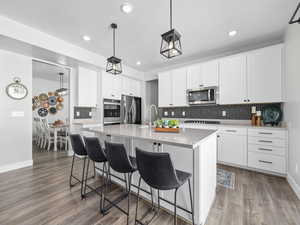 Kitchen featuring a kitchen island with sink, recessed lighting, backsplash, a breakfast bar, and appliances with stainless steel finishes