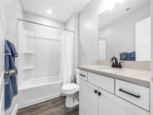 Bathroom featuring wood finished floors, visible vents, toilet, vanity, and shower / bath combo with shower curtain
