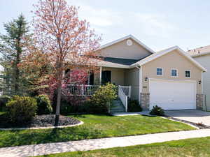 CHARMING Ranch-style home with concrete driveway, a two-car attached garage, and a front yard View of pretty spring.
