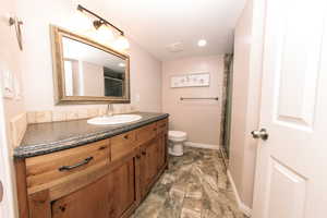 Downstairs Bathroom featuring a toilet, an enclosed shower, a vanity, and a tile floor.