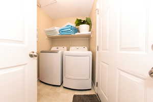 Laundry area featuring washer and dryer, laundry area, and light tile flooring.