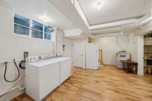 Laundry room featuring light wood finished floors, a textured ceiling, washing machine and clothes dryer, and laundry area