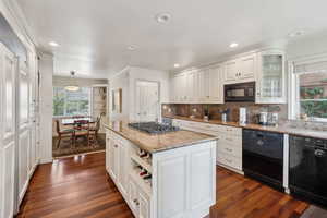 Kitchen with black appliances, dark wood-style flooring, crown molding, and white cabinets