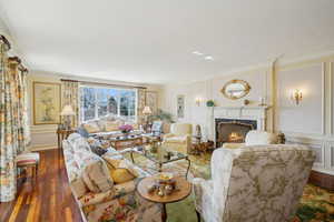 Living area with a premium fireplace, wood finished floors, and ornamental molding