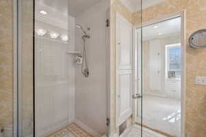Bathroom featuring a shower stall, crown molding, wallpapered walls, and recessed lighting