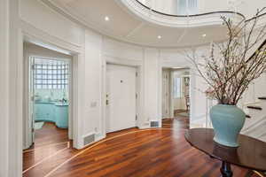 Entrance foyer with visible vents, wood finished floors, a wealth of natural light, and a decorative wall