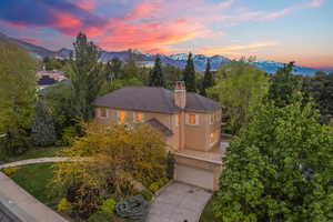 View of front of home with a chimney, driveway, a mountain view, a garage, and stucco siding