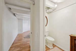 Bathroom with toilet, wood finished floors, and baseboards