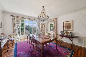 Dining area featuring a wainscoted wall, wood finished floors, a chandelier, and crown molding
