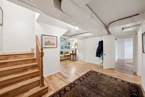 Entryway with baseboards, light wood-style floors, and stairway