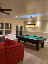 Playroom featuring a textured ceiling, carpet flooring, pool table, and a ceiling fan