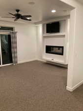 Master bedroom featuring dark carpet, baseboards, a glass covered fireplace, and recessed lighting